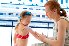 children girl with mother applying sunscreen